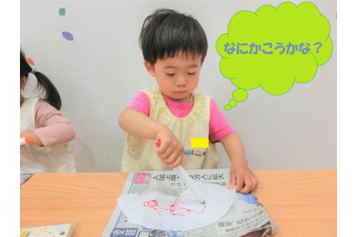 続いて、<span style='color:#ffaf60;'>コーヒーフィルター</span>を使って傘作り！<br>「好きな模様描いてね」と伝えると<br><span style='color:#bc7aff;'>点</span>や<span style='color:#ff75ff;'>丸</span>、<span style='color:#bcff7a;'>顔</span>を描く子どももいました。<br>