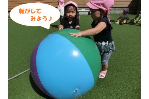 園庭に出ると<span style='color:#ff007f;'>大きなボール</span>が!<br><br>ボールが大好きな子ども達は<br>早速<span style='color:#ff7f00;'>コロコロ転がして</span>いると…<br>