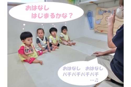 おはなしが始まる前に<span style='color:#ff007f;'>手遊び</span>で<br>「おはなし、おはなし、パチパチパチパチ…」と<br><span style='color:#ff7f00;'>先生</span>が始めると壁に<span style='color:#bc7aff;'>ぺったん</span>と座って<br>一緒に真似っこ<span style='color:#7abcff;'>♬</span>