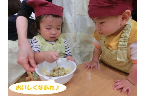 <span style='color:#ff007f;'>エプロン</span>と<span style='color:#ff7f00;'>三角巾</span>をつけて<br>クッキングスタート<span style='color:#ff0000;'>♪</span><br><br>今回はさつまいもを使って<br><span style='color:#7f00ff;'>「さつまいも茶巾」</span>作り！<br><br>まずは<span style='color:#00ff00;'>事前にふかして</span>小さく切っておいた<br><span style='color:#7f00ff;'>さつまいも</span>をフォークで潰しました！<br>