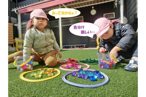 子ども達だけであそびを発展させてくれることも多く<br>フープとキラキラ光る宝石の玩具を用意すると<br><span style='color:#ff7f00;'>「色に分けてみようよ！」</span>と<br>黙々と色分け<span style='color:#ffff00;'>★</span><br>自分たちでルールを作って<br><span style='color:#7f00ff;'>「この色はどっちがいいかなぁ？」</span>と<br>相談して遊ぶ姿も増えました！<br>