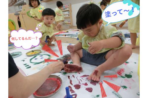 こちらでは<span style='color:#7f00ff;'>足裏に絵の具を塗って</span>は<br>足形をぺたん!<br><br>お友だちが遊ぶ様子をジーっと観察して<br><span style='color:#007fff;'>たのしそう♪</span>と真似っこする姿も。<br>