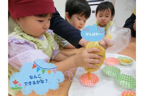 材料を全部入れて<br><span style='color:#b5ff6b;'>もみもみ出来たら…</span><br>端を切って絞りにします！<br>先生と一緒に<br><span style='color:#ff75ff;'>カップに「ぎゅー！」</span><br>順番待ちのお友だちも<br><span style='color:#7575ff;'>興味津々の様子でした！</span>