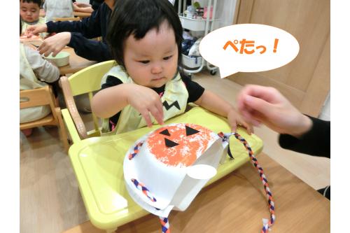 今回の<span style='color:#ba75ff;'>ハロウィン</span>は<br><span style='color:#ffba75;'>ジャックオーランタンのかばん</span>を<br>手作りしました!<br><br>絵の具で紙皿に色をつけて<br>顔を貼り付けて<span style='color:#ff75ba;'>かんせいー!</span><br>指先で器用につまんで<br>先生と一緒に貼り付けた<br><span style='color:#ff007f;'>ひよこチーム(0歳児)</span>